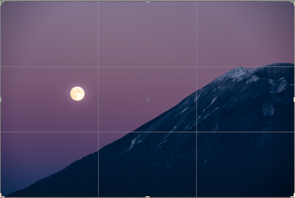 a photo of the moon placed next to Mt. Yotei using the rule fo third for compostion, the image a grid to illustrate the rule of thirds